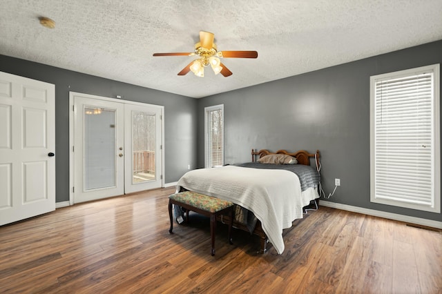 bedroom with french doors, a textured ceiling, access to outside, dark hardwood / wood-style floors, and ceiling fan