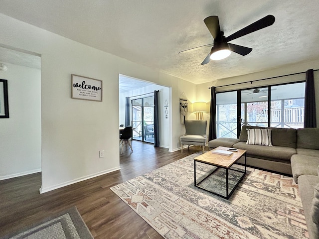 living room with ceiling fan, dark hardwood / wood-style floors, and a textured ceiling