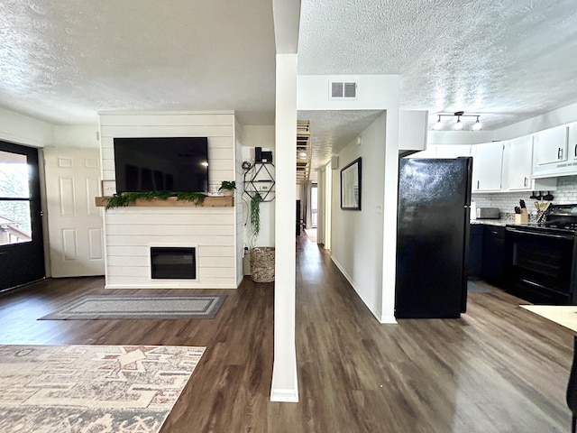 living room featuring dark hardwood / wood-style flooring, a fireplace, rail lighting, and a textured ceiling