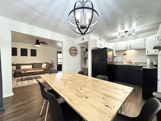 dining area with sink, ceiling fan with notable chandelier, dark hardwood / wood-style floors, and a textured ceiling