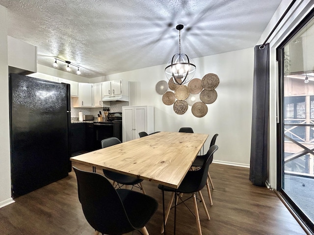 dining room featuring track lighting, a chandelier, a textured ceiling, and dark hardwood / wood-style flooring