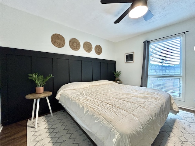 bedroom with ceiling fan, hardwood / wood-style flooring, and a textured ceiling