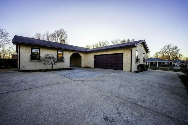 view of front facade with a garage, concrete driveway, and stucco siding