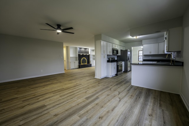 kitchen with ceiling fan, open floor plan, stainless steel appliances, a stone fireplace, and a sink