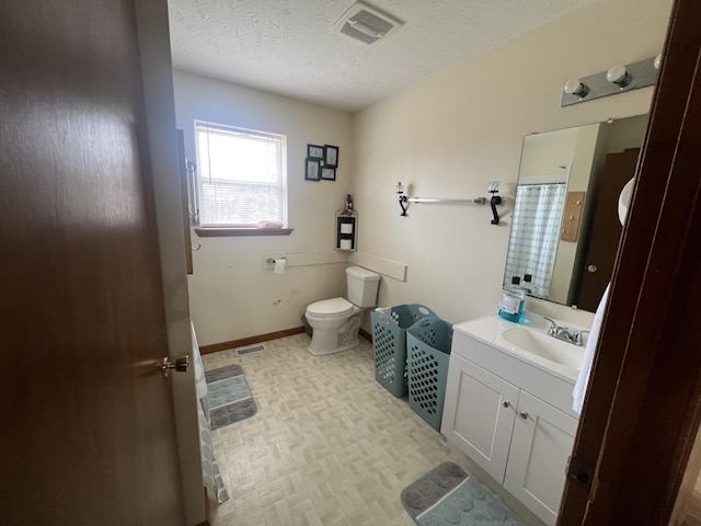 bathroom featuring vanity, toilet, and a textured ceiling