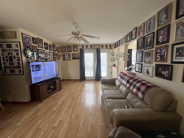 living room with ceiling fan, a textured ceiling, and light hardwood / wood-style flooring