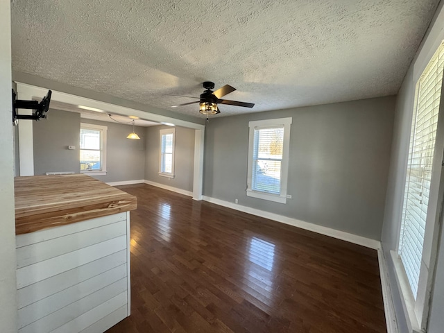 unfurnished living room with ceiling fan, dark hardwood / wood-style flooring, and a textured ceiling