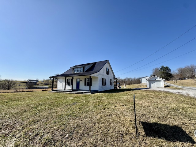 view of front facade featuring a porch, a garage, an outdoor structure, and a front yard