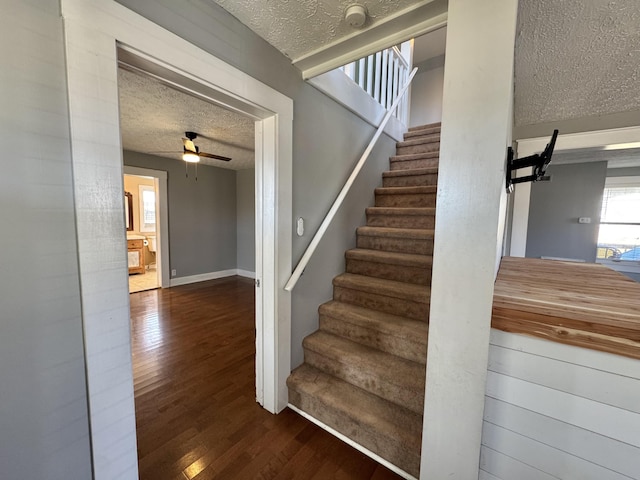 stairway featuring hardwood / wood-style flooring, ceiling fan, and a textured ceiling