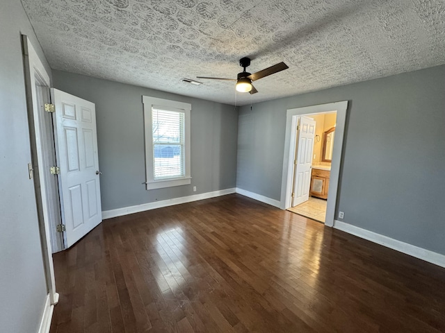 unfurnished bedroom featuring ceiling fan, ensuite bath, dark hardwood / wood-style floors, and a textured ceiling