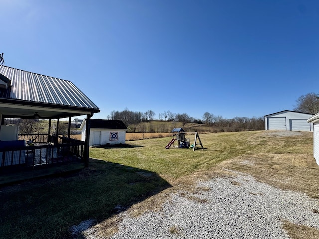 view of yard featuring a garage, a playground, and a storage unit