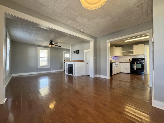 unfurnished living room featuring a textured ceiling, dark hardwood / wood-style floors, and ceiling fan