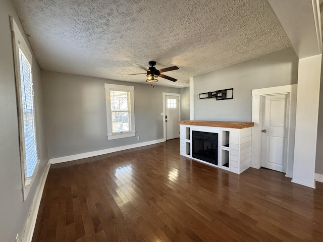 unfurnished living room with ceiling fan, dark hardwood / wood-style flooring, and a textured ceiling