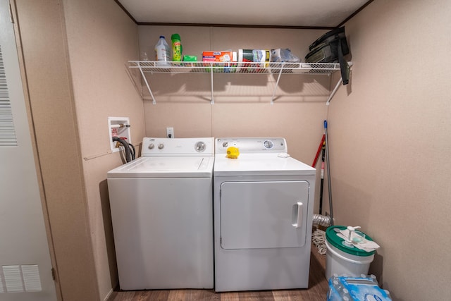 washroom with hardwood / wood-style flooring and washing machine and clothes dryer