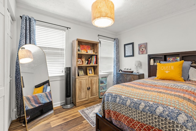 bedroom with hardwood / wood-style floors, ornamental molding, and a textured ceiling