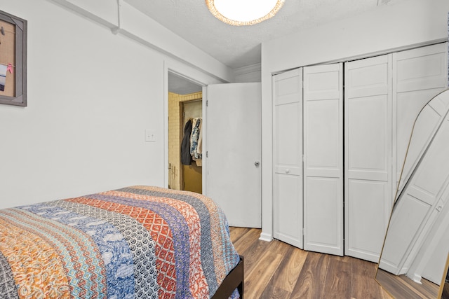 bedroom featuring dark wood-type flooring, a closet, and a textured ceiling