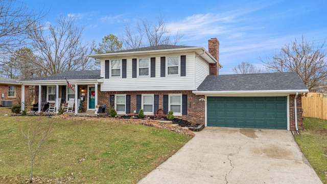 split level home with cooling unit, a garage, a front yard, and covered porch