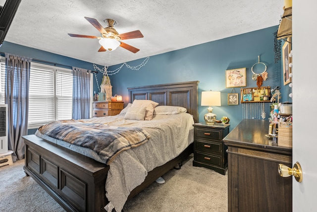 carpeted bedroom featuring ceiling fan and a textured ceiling