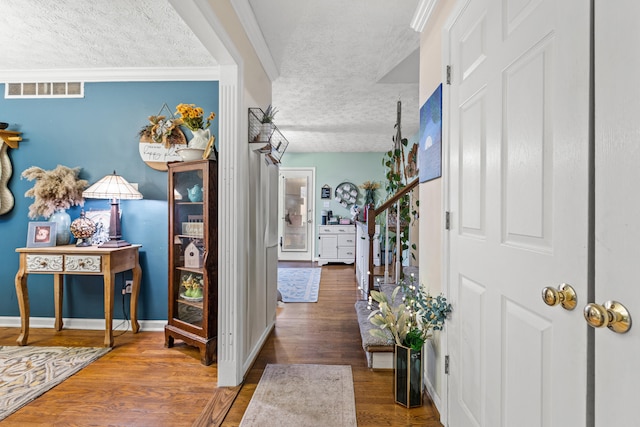 entrance foyer with dark hardwood / wood-style flooring, ornamental molding, and a textured ceiling