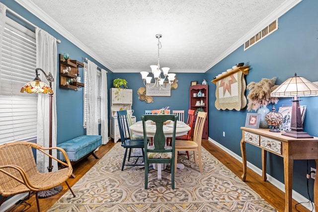 dining space featuring ornamental molding, hardwood / wood-style floors, a notable chandelier, and a textured ceiling