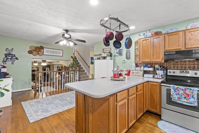 kitchen with stainless steel electric stove, kitchen peninsula, and a textured ceiling