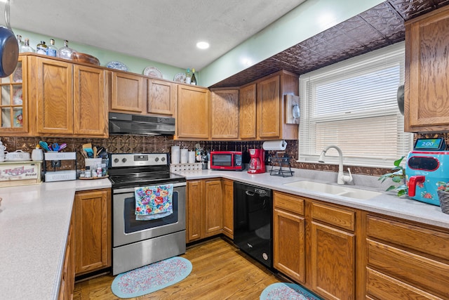 kitchen featuring sink, stainless steel electric range oven, light wood-type flooring, dishwasher, and decorative backsplash