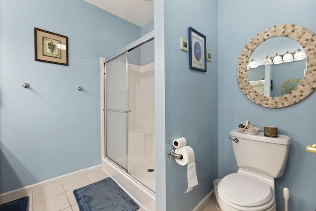 bathroom with tile patterned floors, toilet, and a shower with door