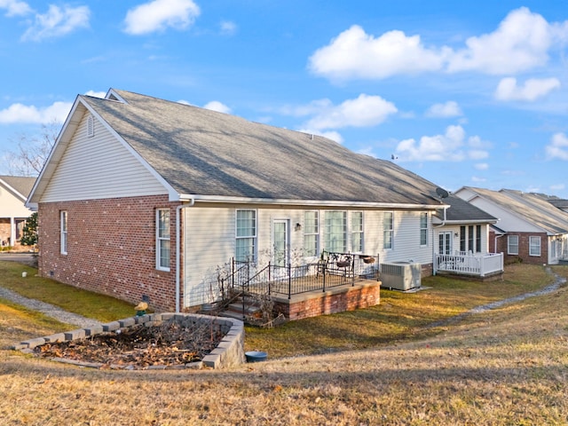 view of front of house with a wooden deck, central AC unit, and a front yard