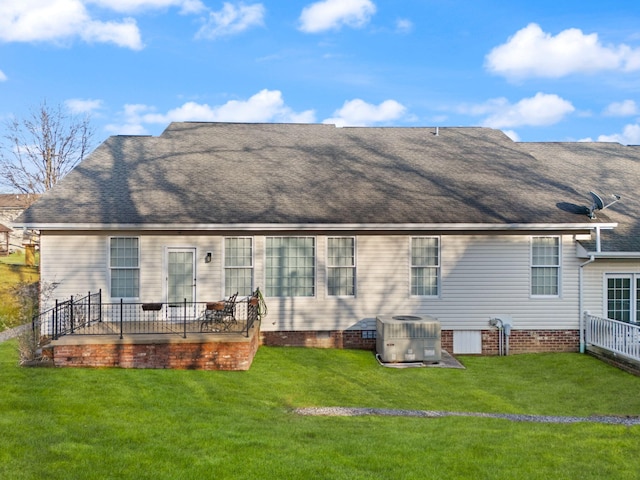 back of property with central AC and a lawn