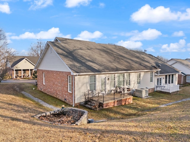 back of property with cooling unit, a yard, and a deck