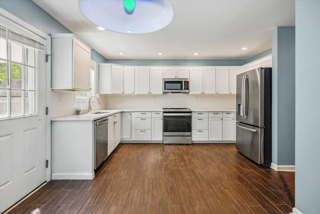 kitchen featuring sink, appliances with stainless steel finishes, white cabinets, dark hardwood / wood-style flooring, and decorative backsplash