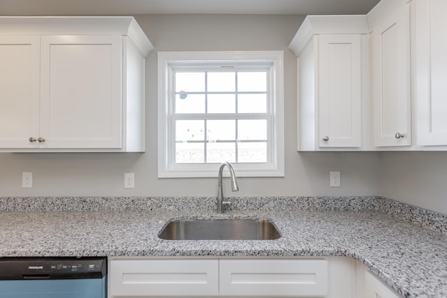 kitchen with dishwasher, sink, white cabinets, and light stone counters