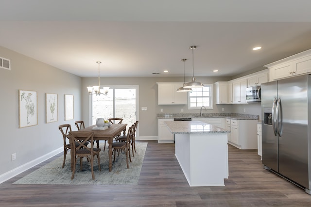 kitchen with pendant lighting, white cabinetry, stainless steel appliances, and a kitchen island