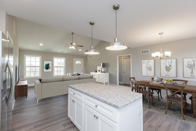 kitchen with white cabinetry, light stone counters, dark hardwood / wood-style flooring, stainless steel fridge with ice dispenser, and vaulted ceiling