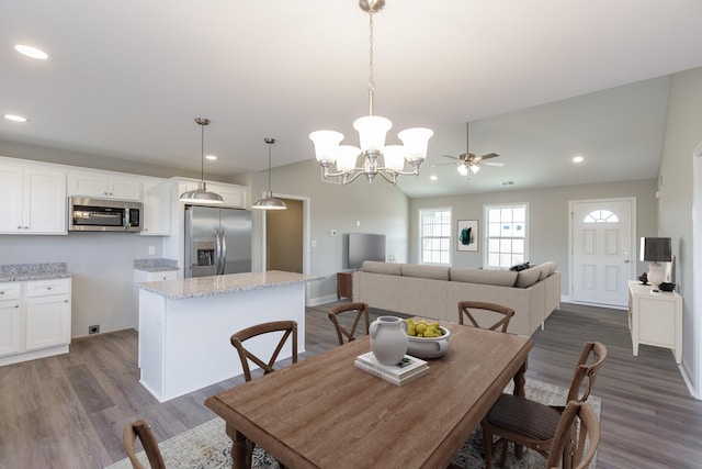 dining room with dark wood-type flooring, ceiling fan, and vaulted ceiling