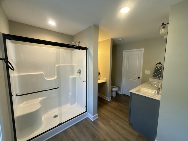 bathroom with hardwood / wood-style flooring, vanity, toilet, and walk in shower