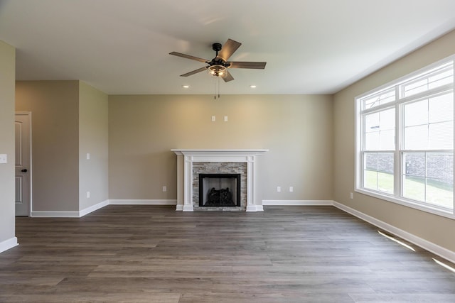 unfurnished living room featuring dark wood-type flooring, ceiling fan, and a fireplace