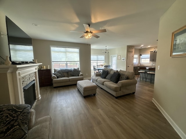 living room featuring a stone fireplace, a wealth of natural light, and dark hardwood / wood-style floors