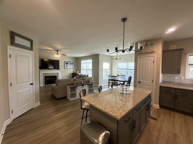 kitchen featuring light stone counters, decorative light fixtures, dark hardwood / wood-style floors, a kitchen breakfast bar, and a kitchen island