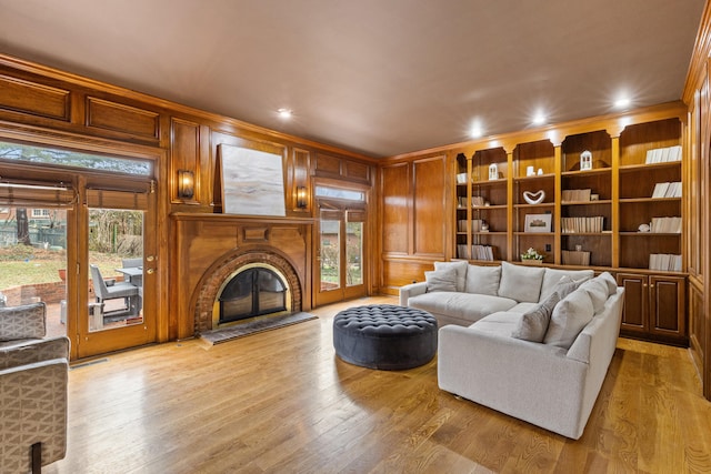 living room featuring crown molding, light hardwood / wood-style flooring, and wooden walls