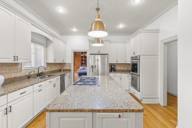 kitchen featuring sink, a center island, hanging light fixtures, stainless steel appliances, and white cabinets