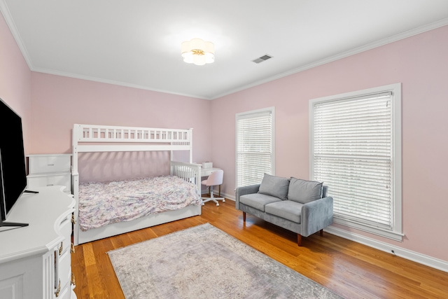 bedroom featuring multiple windows, ornamental molding, and light hardwood / wood-style floors