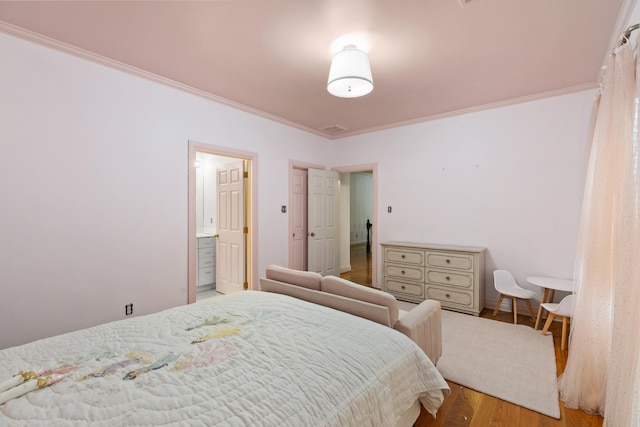 bedroom with crown molding, wood-type flooring, and connected bathroom