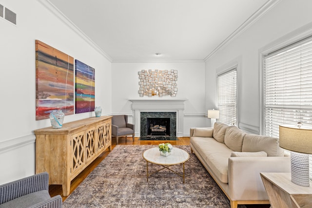 living room with crown molding, wood-type flooring, and a high end fireplace