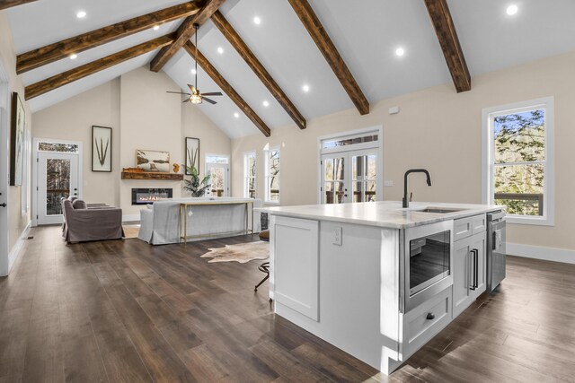 kitchen with built in microwave, french doors, sink, high vaulted ceiling, and a kitchen island with sink