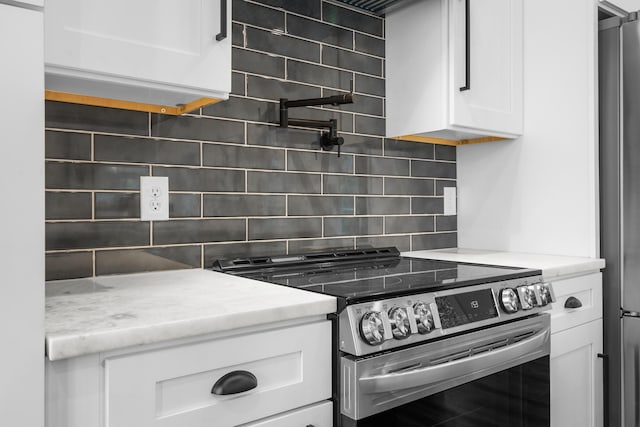 kitchen with backsplash, stainless steel appliances, white cabinets, and light stone countertops