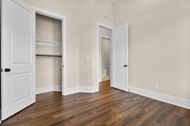 unfurnished bedroom with dark hardwood / wood-style flooring and a closet