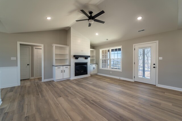 unfurnished living room featuring vaulted ceiling, a fireplace, ceiling fan, and light hardwood / wood-style flooring