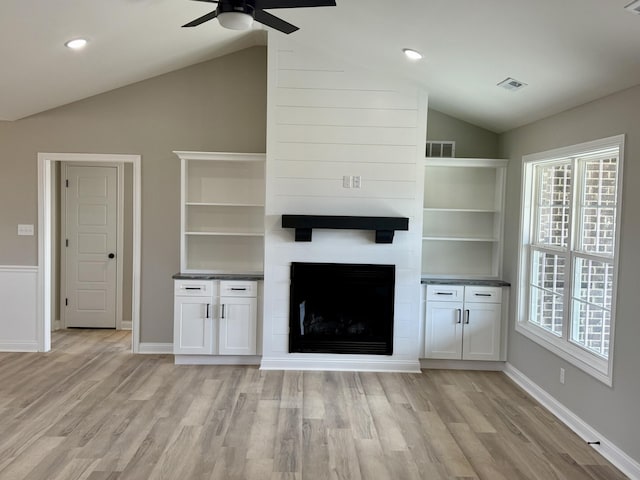 unfurnished living room featuring vaulted ceiling, light wood-type flooring, ceiling fan, and a fireplace