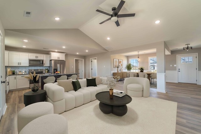 kitchen featuring sink, appliances with stainless steel finishes, a center island, white cabinets, and vaulted ceiling